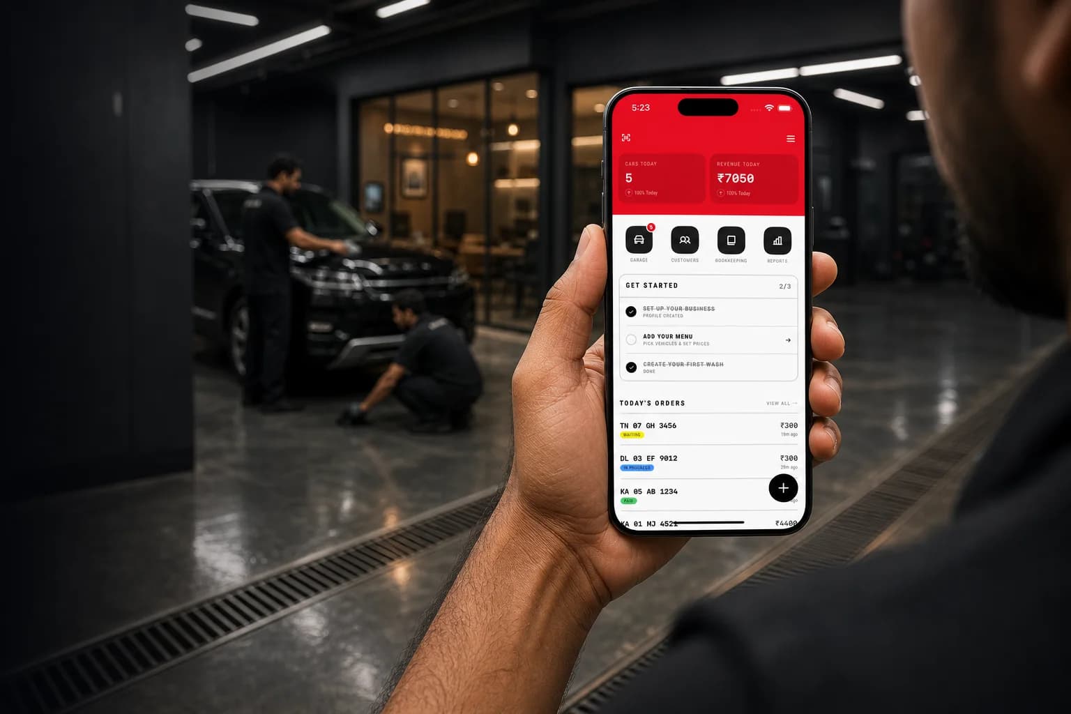 Indian car wash owner holding a phone with the MintWash dashboard open